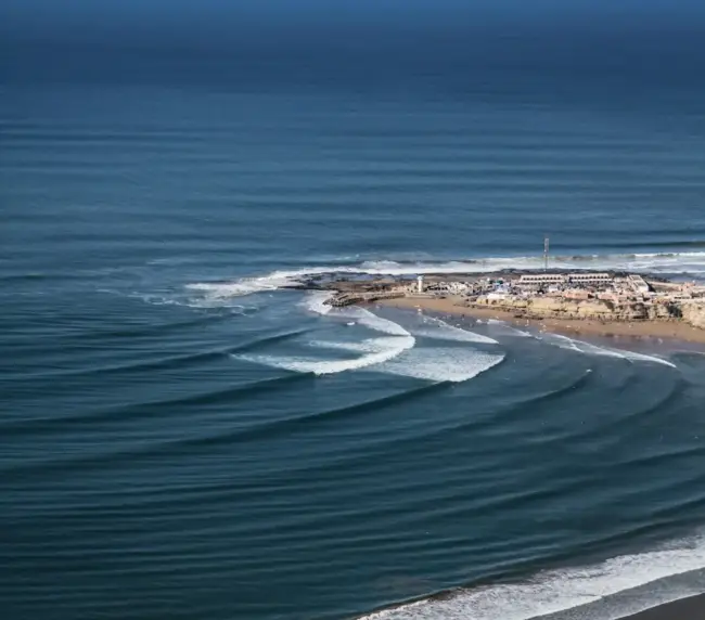 Elevated view of long, clean wave lines wrapping into the Bay point break at Imsouane.