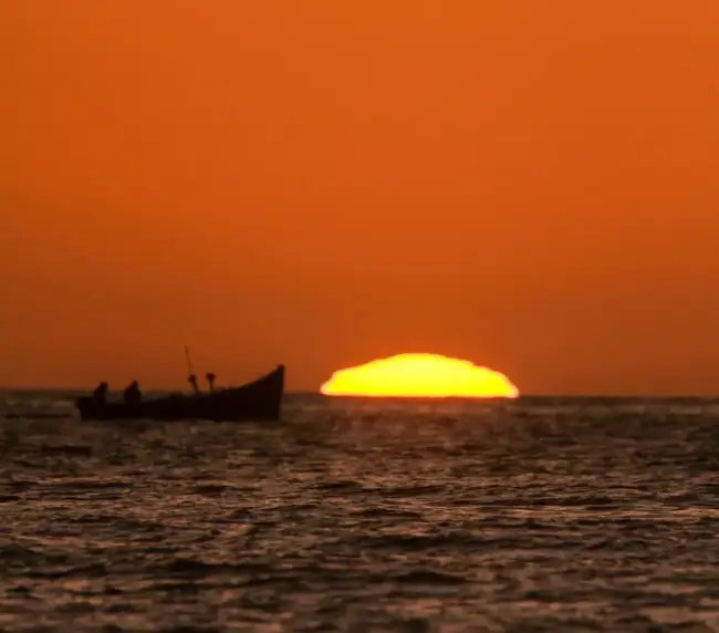 Fishing boat silhouetted on the Atlantic as the sun sets into the water off Imsouane.